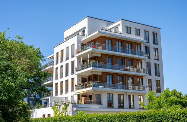 Beautiful four story white and brown condo building surrounded by greenery and protected by Selective Insurance.